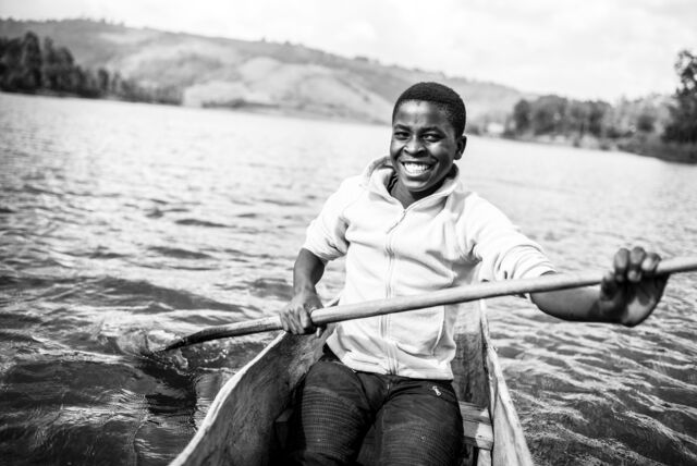 Fotograf aus dem Engadin zeigt ein Junge in einem Boot, sitzend, lachend und rudernd.